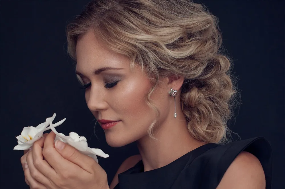 Woman with beatiful blonde hair holding orchids in her hand.